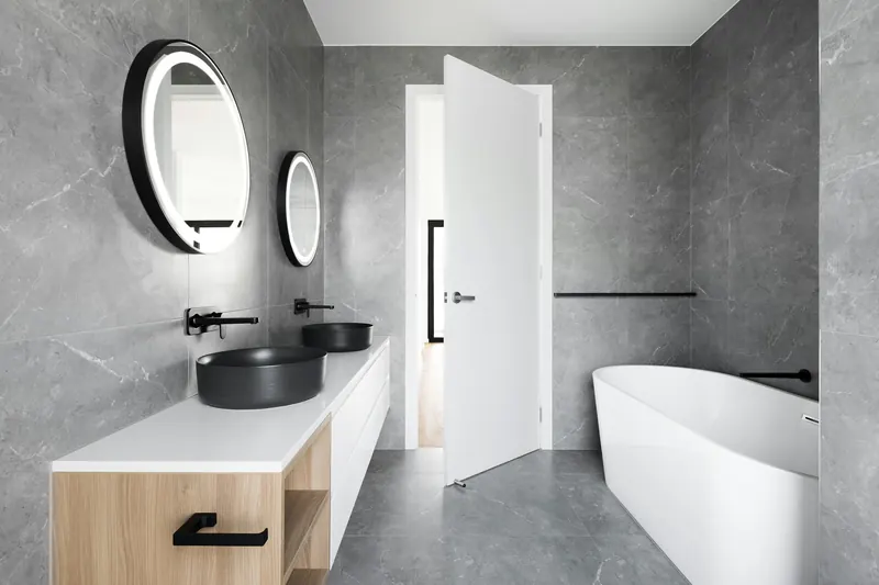 Bathroom in grey stone with a freestanding tub and timber vanity